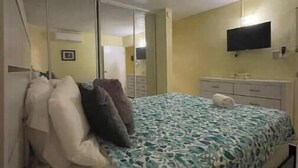 Una camera da letto con un letto, una TV a muro, uno specchio e un armadio.