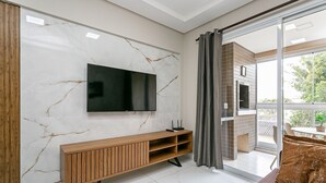 Ein modernes Wohnzimmer mit Marmorwand, einer Holz-Unterhaltungsecke, einem Flachbildfernseher und einer Glastür zum Außenbereich.