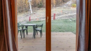 Une pièce dotée d’une porte-fenêtre coulissante donnant sur une terrasse extérieure avec une table et des chaises.