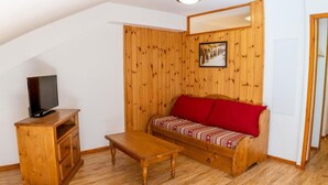 A cozy room with a wooden sofa, a TV on a wooden cabinet, and a small wooden table.