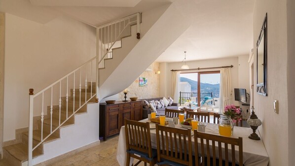 A spacious living area with a dining table set for four, a staircase, and a view of the outdoors. - Elena Is A Contemporary, Spacious Apartment Within The Stunning Elvina Complex (Kalkan, Antalya)