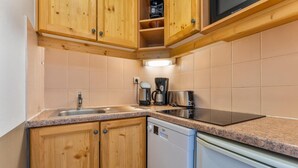 Eine kleine Küche mit Holdekor, einem integrierten Geschirrspüler und einer Arbeitsplatte mit Kaffeemaschine und Toaster.