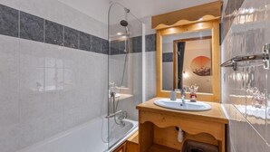 A bathroom with a glass-enclosed shower, a wooden vanity with a sink, and a mirror above it.