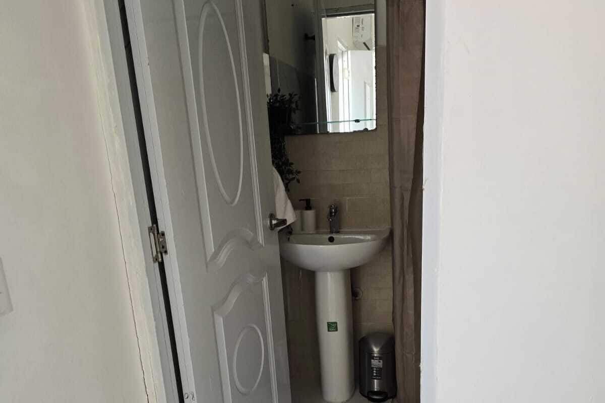 Un baño con lavamanos blanco, un espejo y una cortina de ducha.