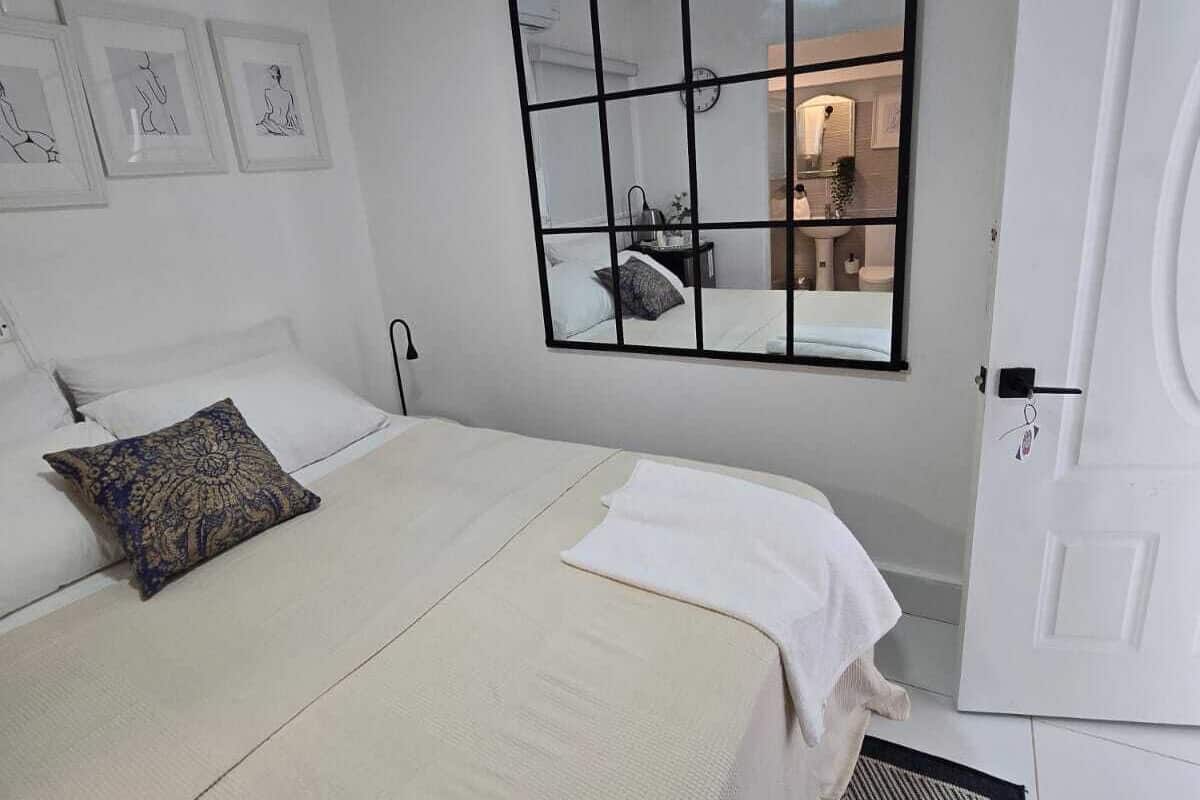 Un dormitorio con cama, mesita de noche, espejo y puerta.