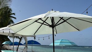 Un'ambientazione sulla spiaggia con tavoli da picnic e ombrelloni, con vista sull'oceano.