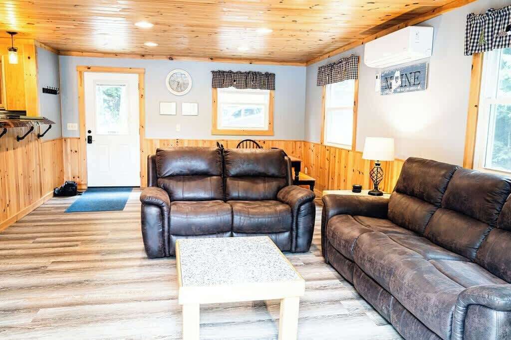 En hyggelig stue med en brun lædersofa, et træbord og en pejs.