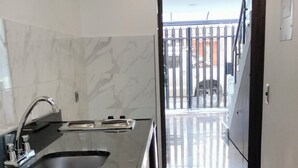 Eine moderne Küche mit Marmor-Spritzschutz, einer Holzeile und Blick auf ein bewachtes Grundstück durch eine offene Tür.