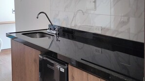Eine moderne Küche mit Holzschränken, einer schwarzen Arbeitsplatte und einem eingebauten Geschirrspüler.