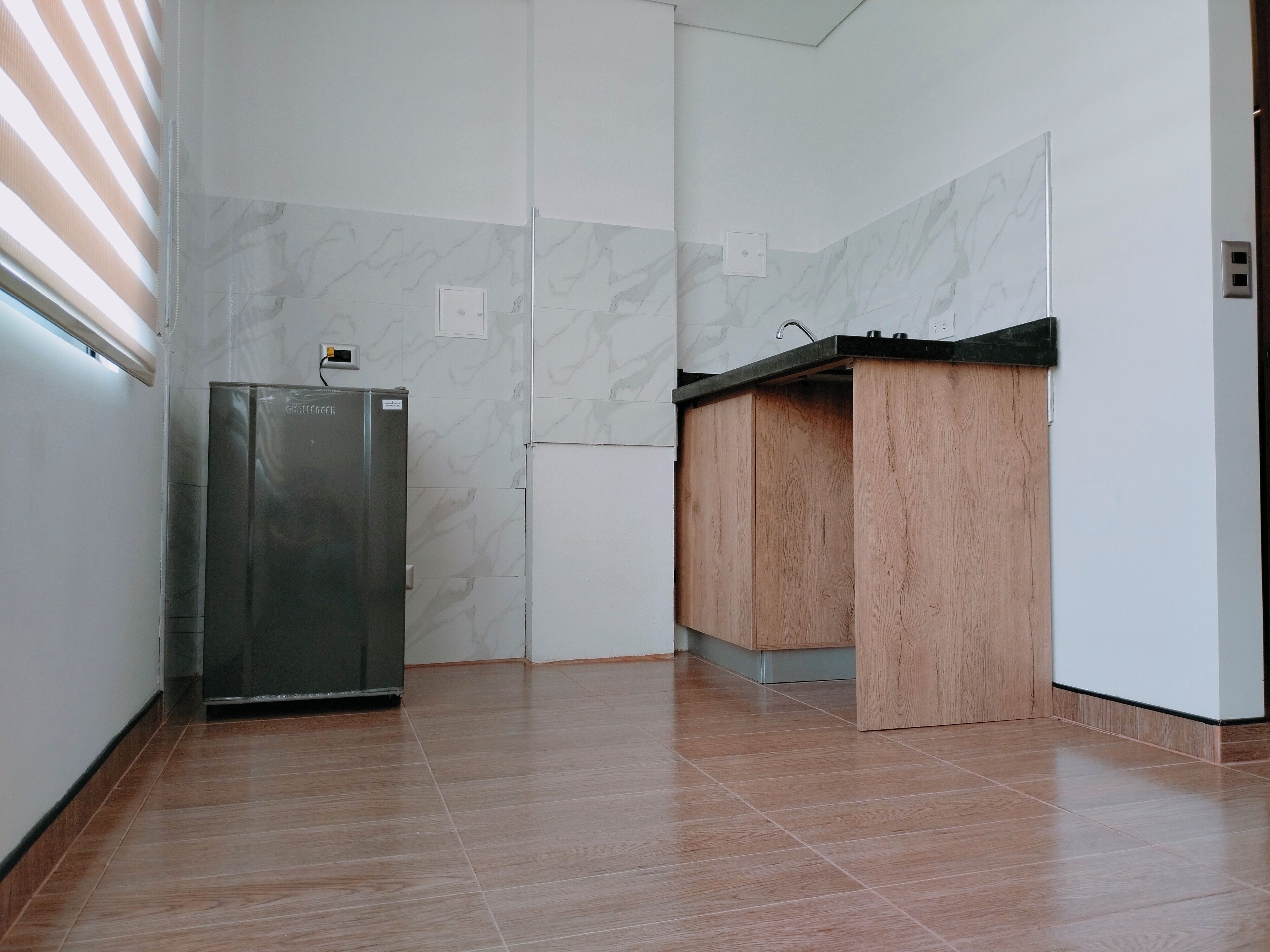 Een moderne keuken met een inbouwkoelkast, houten kastjes en een marmeren achterwand.