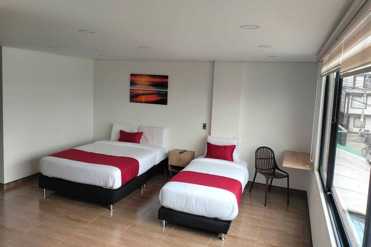 Een moderne hotelkamer met twee bedden, een bureau en een raam met uitzicht op de straat.