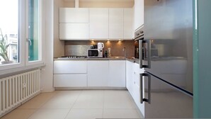 A modern kitchen with white cabinets, a stainless steel refrigerator, a microwave, and a kettle. - 4bnb - Armot House Vatican Apartment (Rome)