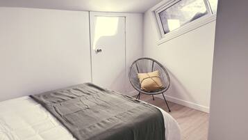 Een slaapkamer met een bed, een stoel, een raam en een deur.