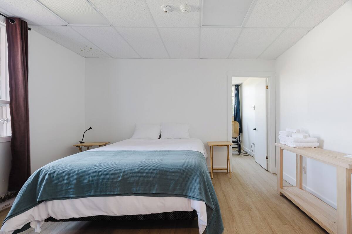 A minimalist bedroom with a bed, bedside tables, a desk, and a chair.