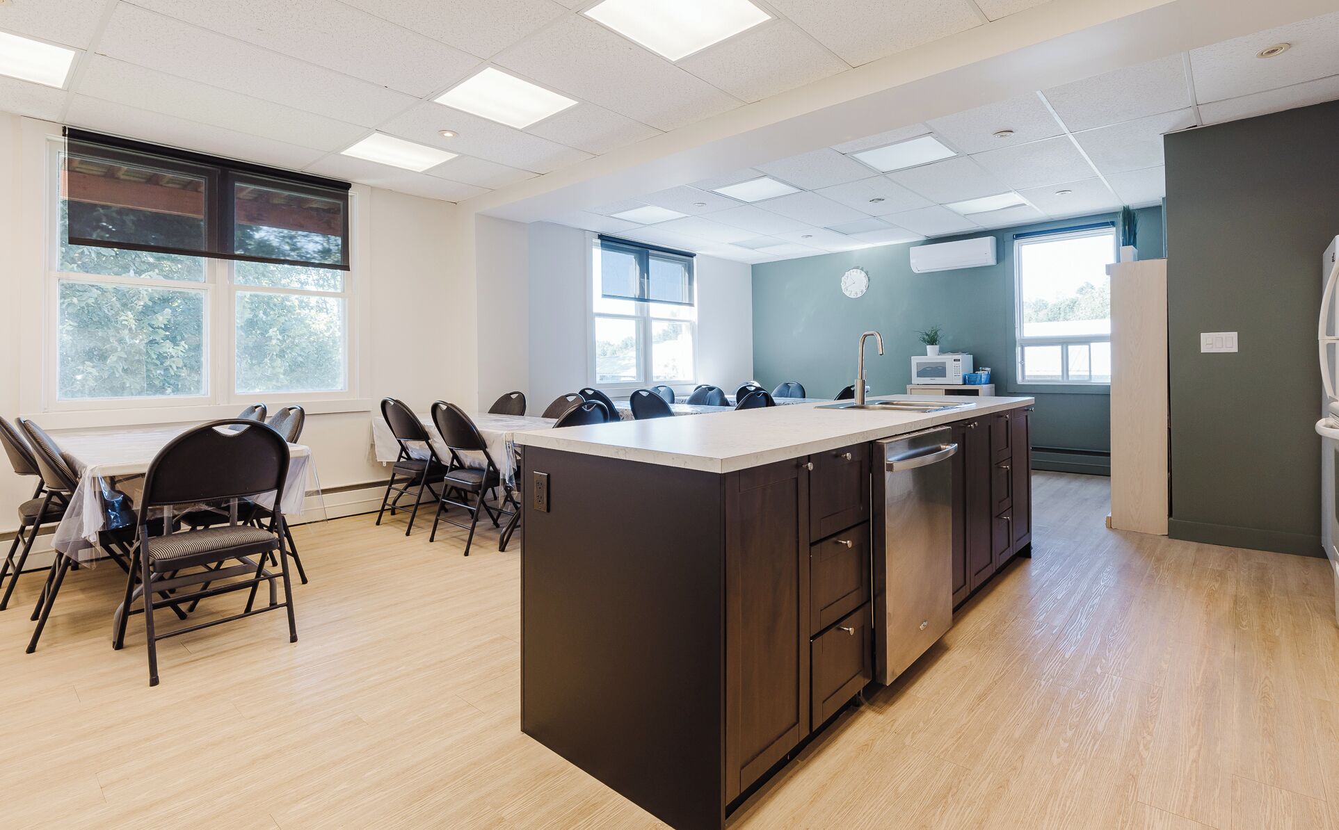 A modern kitchen with a central island, a dining area with chairs, and large windows providing natural light.
