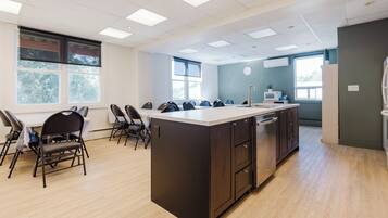A modern kitchen with a central island, a dining area with chairs, and large windows providing natural light.
