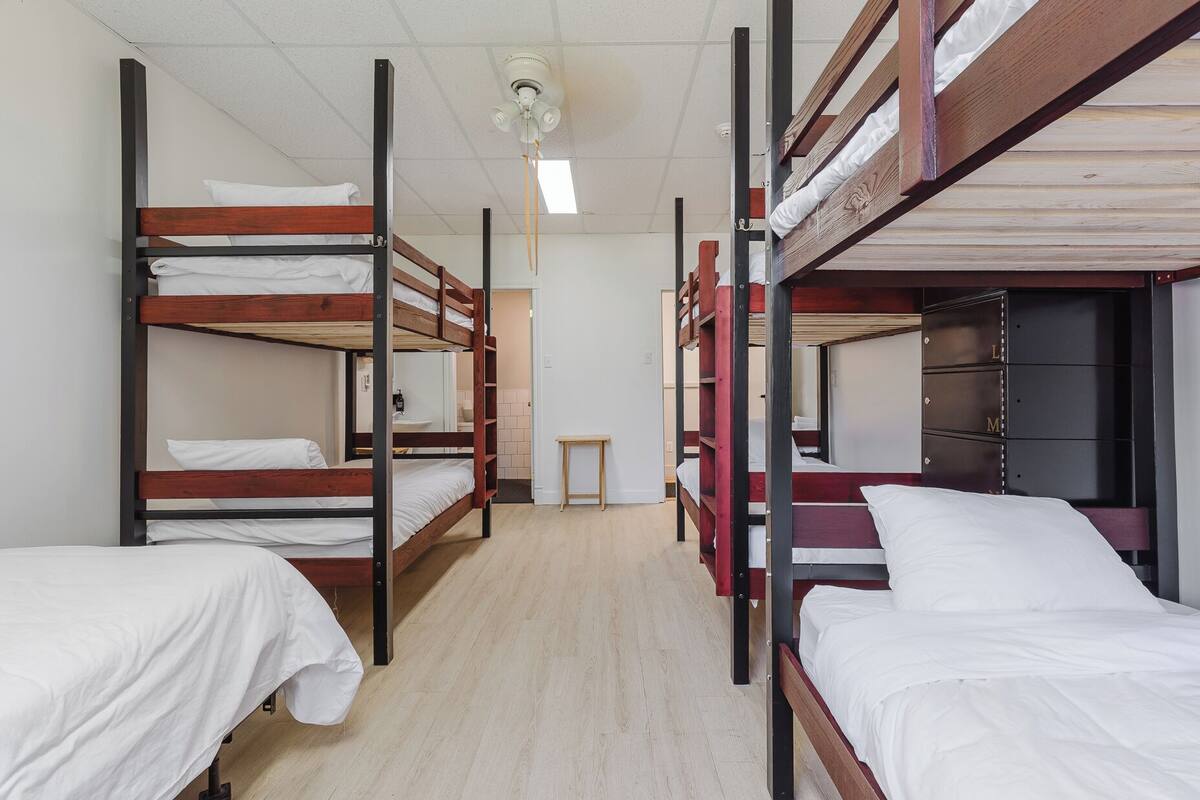 A dormitory room with bunk beds, a small table, and a wardrobe.