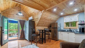 A cozy cabin with a wooden interior, a kitchenette, and a dining area. - Couples Carriage House Retreat - Wineries & Hiking (Dahlonega)
