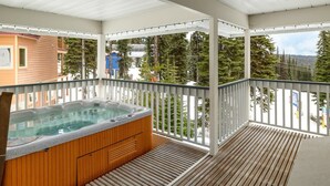 Un jacuzzi sur un balcon, avec vue sur les arbres et un bâtiment en arrière-plan.
