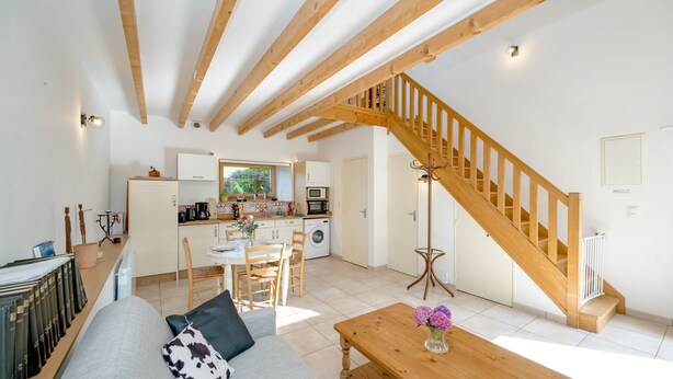 A spacious living area with a wooden staircase, a dining table, and a sofa. - La Maison du Puits Merpault - Avec jardin (Saint-Alban)
