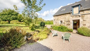 A stone building with a gravel driveway, a wooden fence, and a chair. - La Maison du Puits Merpault - Avec jardin (Saint-Alban)