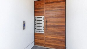 Una puerta de madera con un cartel que indica la entrada al banco Barclays y a apartamentos.