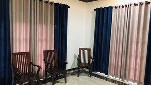 Una habitación con dos sillas de madera, un ventilador de techo y suelo de mármol.