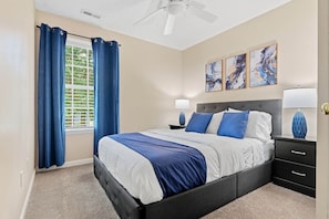 A bedroom with a bed, a nightstand, a lamp, and a ceiling fan.