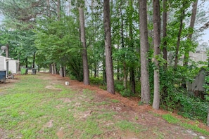 A wooded area with a grassy path and a small building. - 3BR Retreat • Perfect for Groups • Near Downtown (Raleigh)