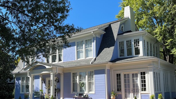 Une grande maison à deux étages, dotée d’un toit à pignon bien visible et de nombreuses fenêtres.
