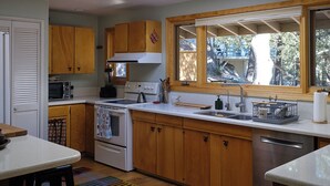 Una cocina con armarios de madera, microondas, estufa y un ventanal grande.
