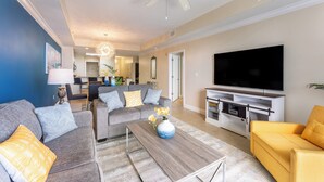 Un salon moderne avec un canapé gris, un fauteuil jaune et un téléviseur à écran plat.
