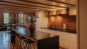 A modern kitchen with a brick backsplash, wooden beams, and a large island with bar stools.