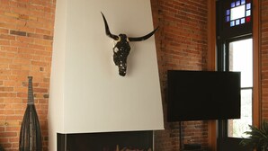 A modern living room with a fireplace, brick walls, and a mounted bull skull decoration.