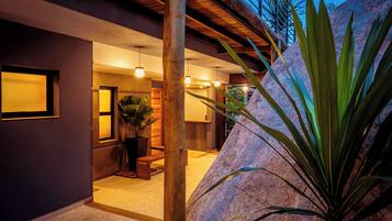 Un intérieur moderne avec un mur d’accent en pierre, des poutres en bois et une plante en pot.