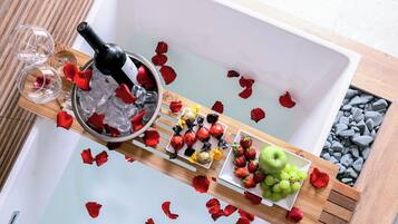 Un plateau avec une bouteille de vin, des verres vides, des fraises, des raisins et des pétales de rose.
