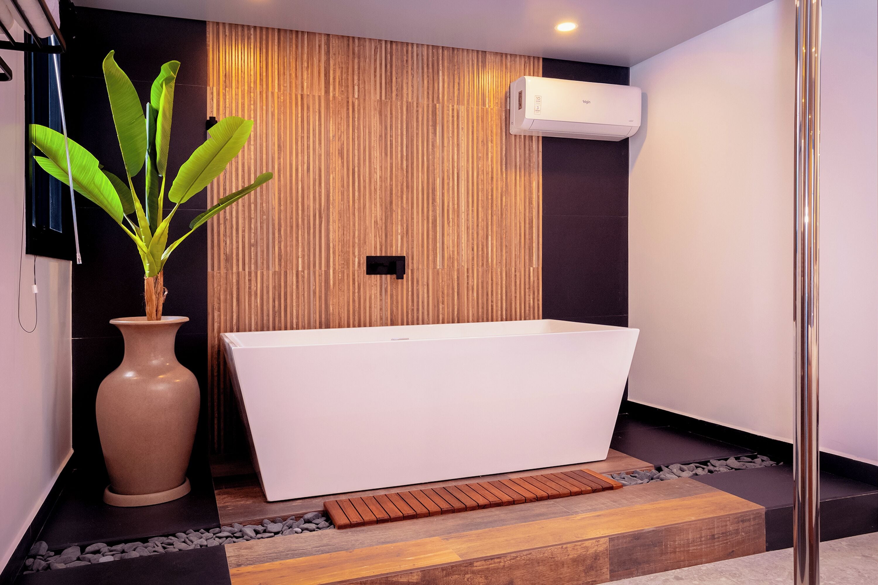 Une salle de bain moderne avec une baignoire sur pieds, un mur recouvert de panneaux en bois et une plante en pot.