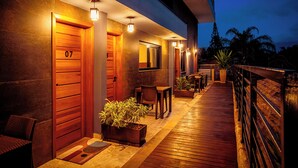 A modern hotel exterior with a wooden deck, outdoor seating, and potted plants. - VELINN 2Secreto Hotel Boutique (Ilhabela)