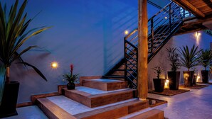 A staircase with wooden steps and a metal railing, surrounded by potted plants and illuminated by wall-mounted lights. - VELINN 2Secreto Hotel Boutique (Ilhabela)