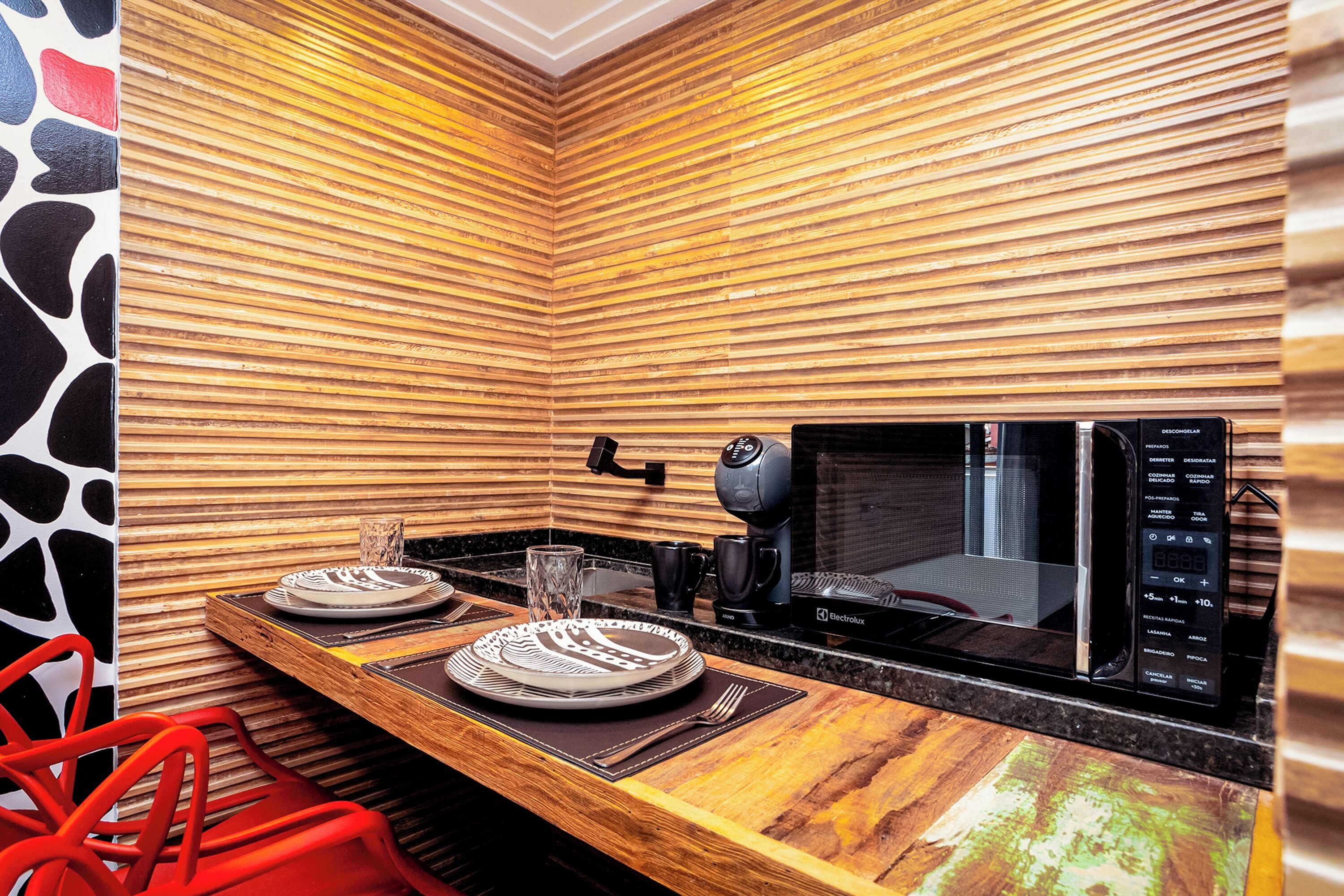 Une cuisine de taille réduite avec un mur en bois, un four à micro-ondes et une machine à café.