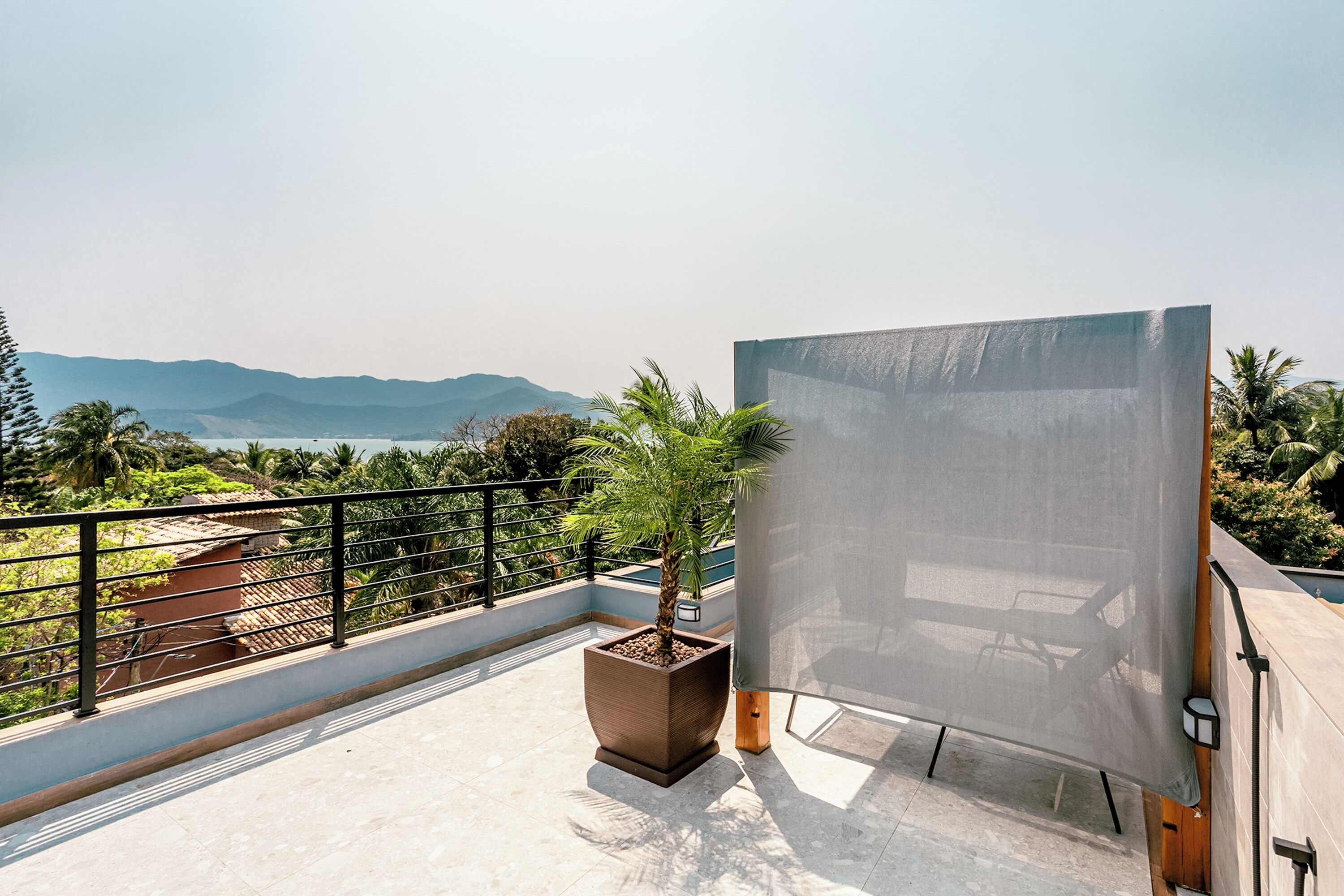 A balcony with a large potted plant, a chair, and a table.