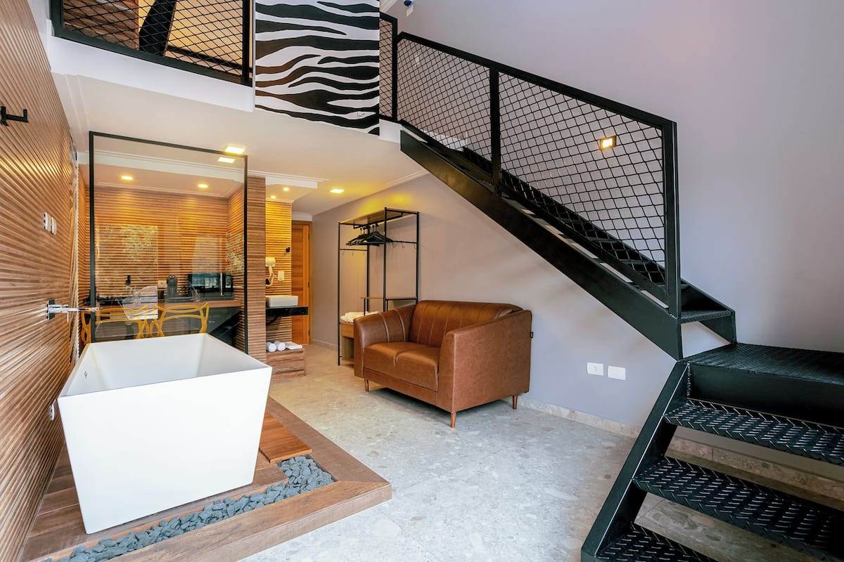 Um interior moderno com uma banheira grande, um sofá de couro e uma escada com corrimão estampado com padrão de zebra.