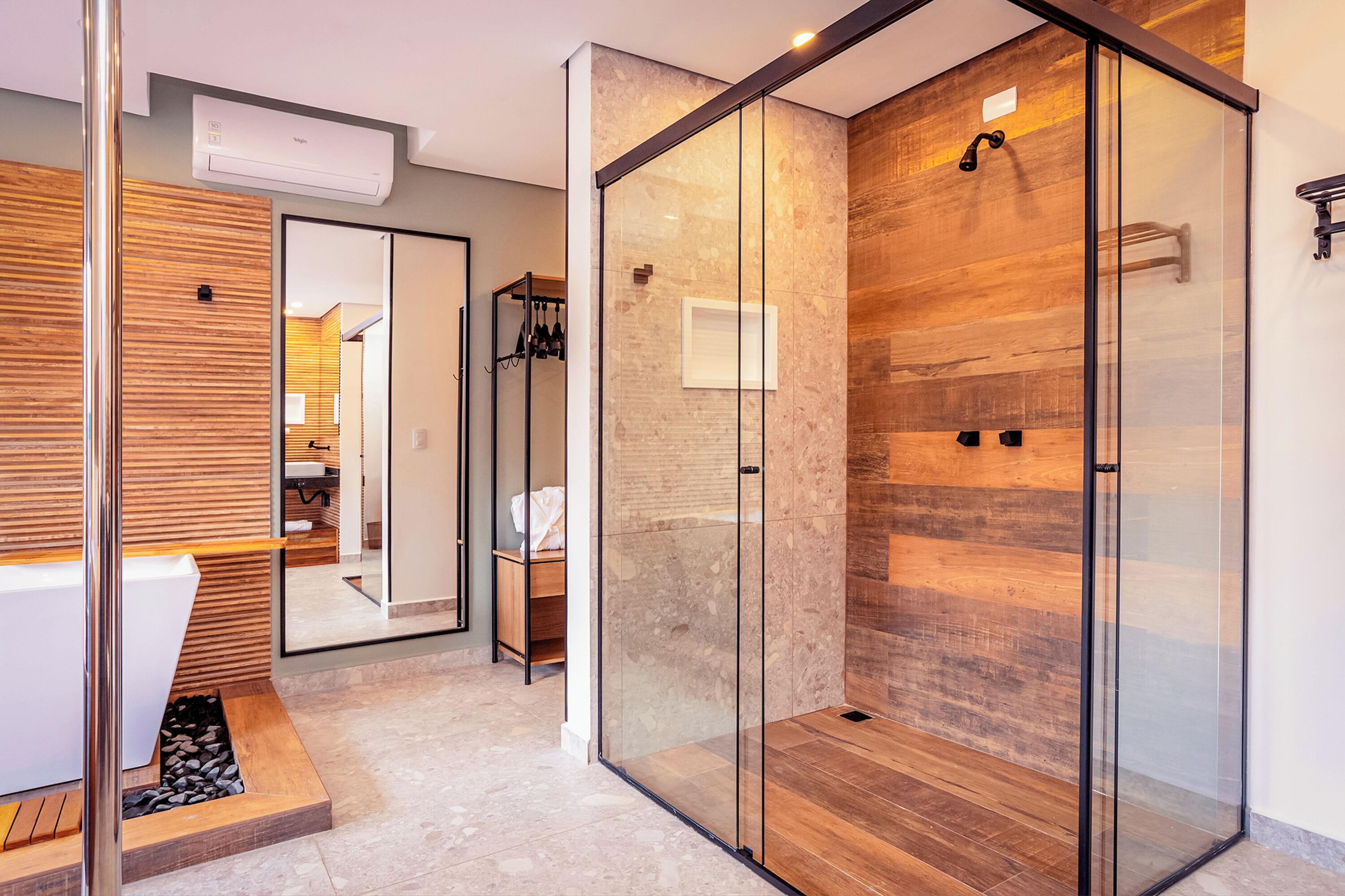 Un baño moderno con cabina de ducha de vidrio, tocador de madera y bañera empotrada.