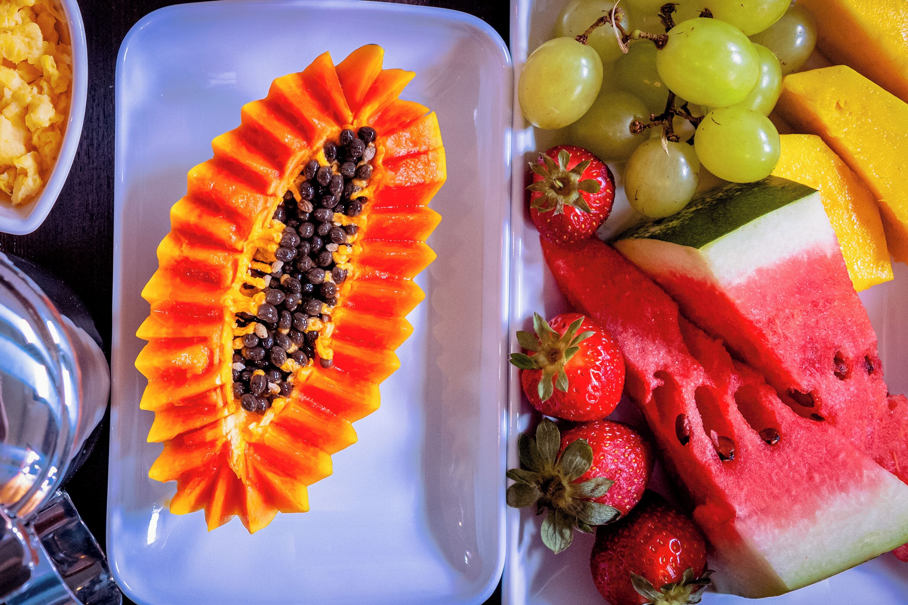 Un assortiment de fruits coupés en tranches, comprenant de la pastèque, des fraises, des raisins et une papaye décorative.