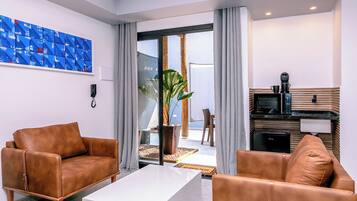 A modern living room with leather sofas, a white coffee table, and a kitchen area with a microwave.