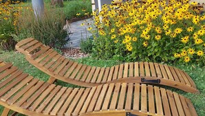 Una terraza de madera con un paraguas blanco, una pared amarilla y una ventana.