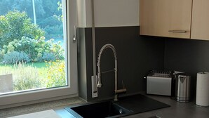 Una cocina con ventana, grifo de acero inoxidable, tostadora y armarios de madera.