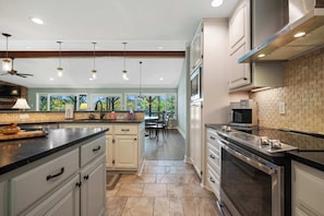 Una cocina moderna con una isla central, electrodomésticos integrados y un comedor con vistas.