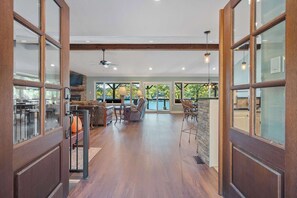 Un interior amplio con comedor, cocina y grandes ventanales que ofrecen vistas al exterior.
