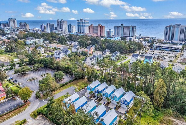 A residential area with houses, a parking lot, and a view of the ocean and city skyline.